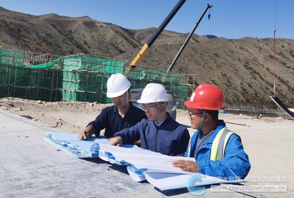 侯争光(左二)在工程现场查看图纸