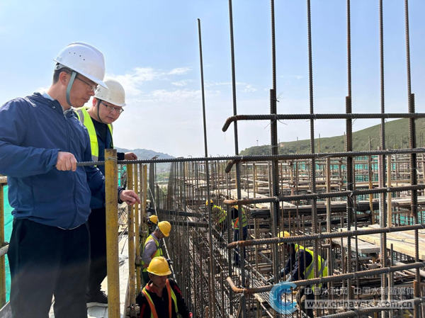 侯争光(左一)在工程现场检查混凝土浇筑仓号